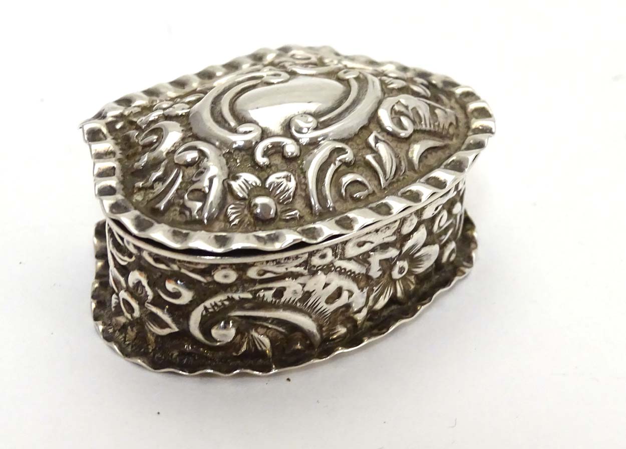 A Victorian silver small box with embossed decoration.