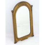 An early 20thC gilt bevelled wall mirror of arched form with pilaster decoration.