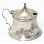 A silver mustard pot with hinged lid and blue glass liner.