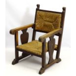 A mid / late 19thC Gothic oak open armchair with rush seat and matching back rest,