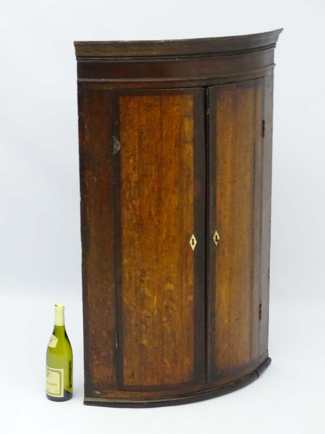 A late 18thC oak bow fronted corner cupboard with mahogany cross banded doors and mahogany frieze - Image 3 of 7