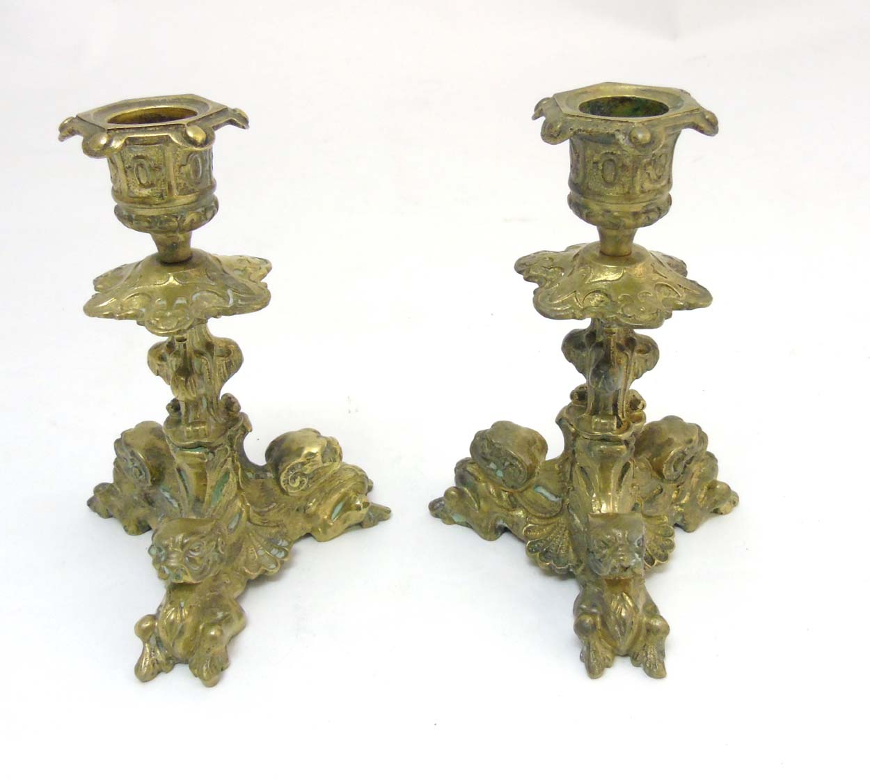 A pair of cast brass tri-form candlesticks having organic formed pedestal and 3 horned beasts to
