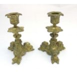 A pair of cast brass tri-form candlesticks having organic formed pedestal and 3 horned beasts to