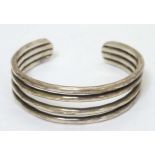 A white metal bangle bracelet of four band form with facet detail.