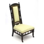 An ebonised Aesthetic Movement nursing chair with floral carving to the cresting rail,