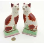 A pair of large Staffordshire cats, decorated with gilt bow decoration,