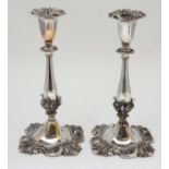 A pair of silver plate candlesticks with scroll decoration.