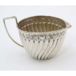 A Victorian silver cream jug with fluted and embossed decoration.