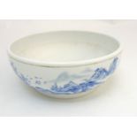 A Chinese blue and white bowl decorated in an underglaze blue continuous landscape and iron red