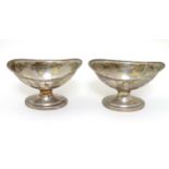 A pair of silver plate pedestal boat shaped table salts .