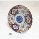 An Oriental Imari style plate with scalloped edges with stylized floral design to centre and other