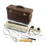A Doctor's leather case containing various instruments including a surgical saw and Kielland's