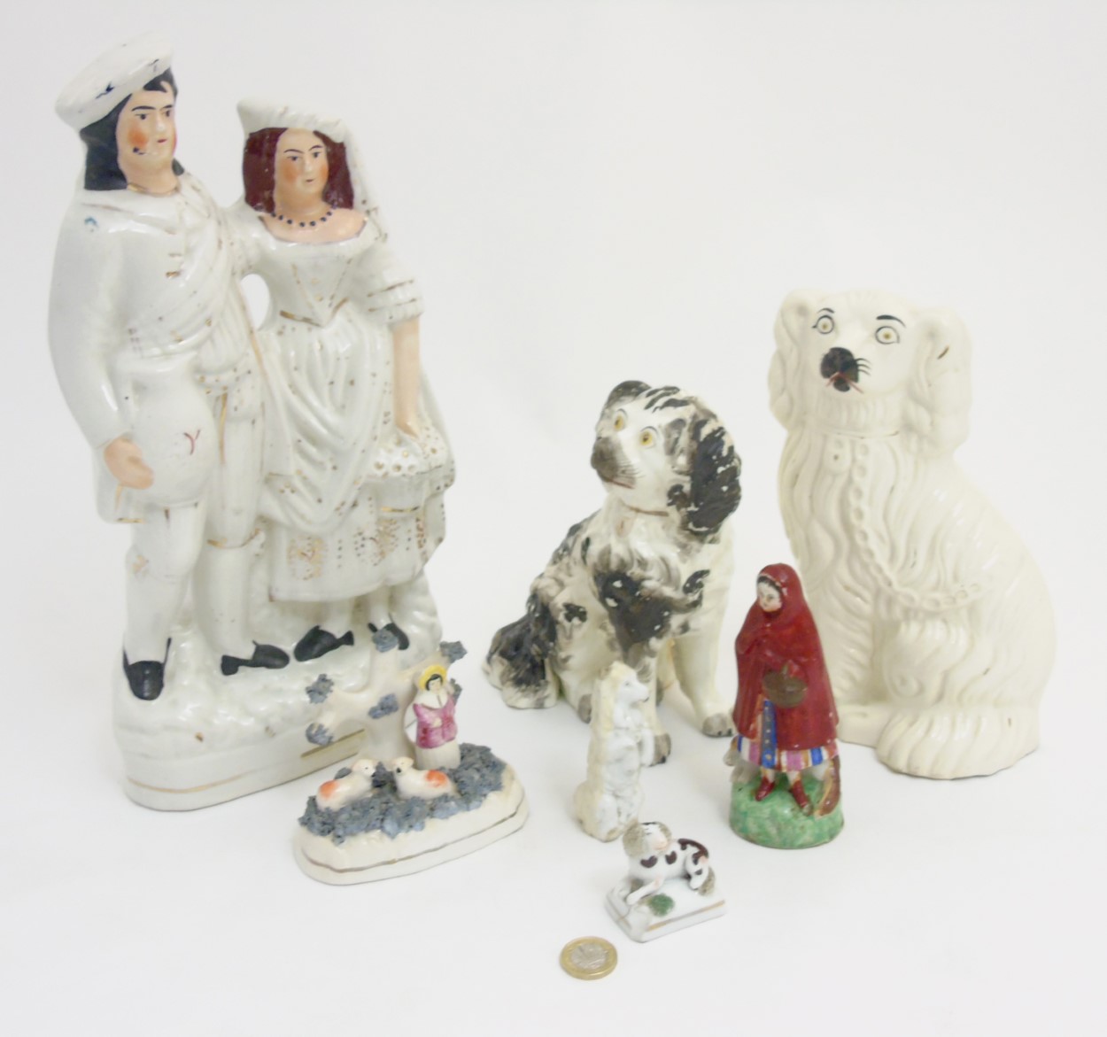 A quantity of Staffordshire items comprising a Scottish couple, a figure and sheep group,
