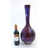 An Oriental Sang de Boeuf Flambé glazed bottle vase with bulbous body and tall tapering cylindrical