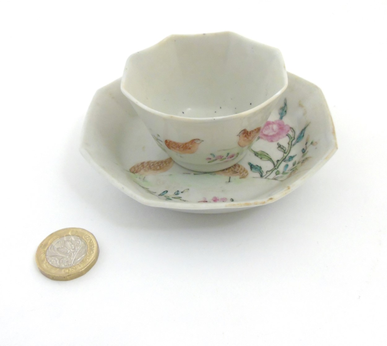 A Chinese Famille Rose octagonal cup and saucer depicting partridges amidst peonies on white ground,