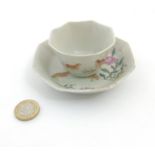 A Chinese Famille Rose octagonal cup and saucer depicting partridges amidst peonies on white ground,