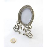 A late Victorian nickel oval photograph frame with ornate 3-footed base.