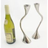 A pair of chromed candlesticks of modernist tendril form.