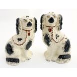 Two Victorian Staffordshire spaniels, with black patch decoration and brown lock and chain,