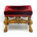 An early 20thC walnut stool with carved stretcher depicting cherubs holding a crown,