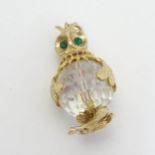 A pendant formed as an owl, the facet cut glass body with yellow metal mounts and green stone eyes.
