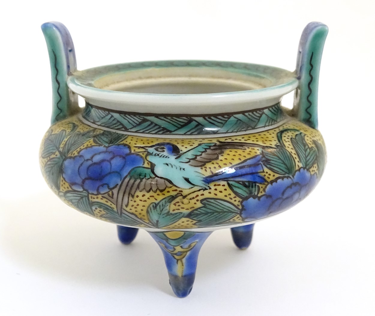 A Chinese three legged, two handled censer, decorated with a bird and flowers.