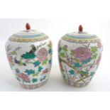 A pair of Famille Rose lidded vases / ginger jars of ovoid form,
