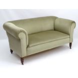 A late 19thC Chesterfield sofa with scrolled arms and standing on turned legs terminating in