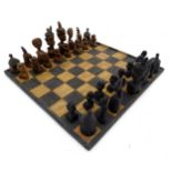 A quantity of carved wooden tribal chess pieces together with a chess board,