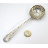 An Irish silver sauce ladle with shell formed bowl and engraved decoration to handle.