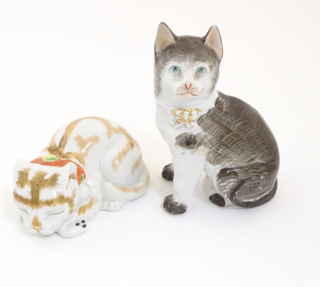 Two ceramic models of cats, one seated, one recumbent. Height of the seated model: approx.