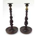 A pair of early 20thC carved oak barley twist and brass candlesticks with drip trays.