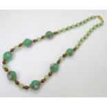 A glass bead necklace of Jade coloured and Venetian glass beads with gilt and enamel decoration.