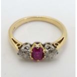An 18ct gold ring set with central ruby flanked by 2 diamonds.
