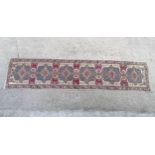 Rug / carpet :a long beige ground runner with 6 geometric motifs and red , blue ,