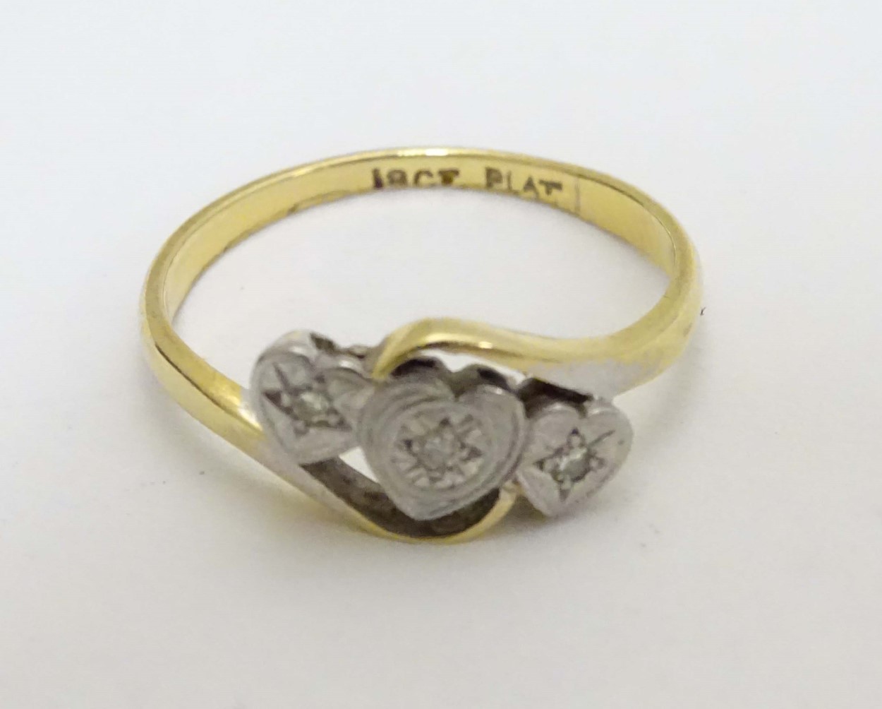 An 18ct gold ring set with three diamonds in a platinum heart shaped setting CONDITION: