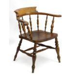 A late 19thC / early 20thC smokers bow / captains chair with shaped backrest and spindle supports,