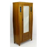 Arts & Crafts: An oak wardrobe with single large mirrored door flanked by leaded stained glass