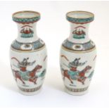 A pair of Chinese rouleau vases decorated with a figure on horseback and a figure with a flag.
