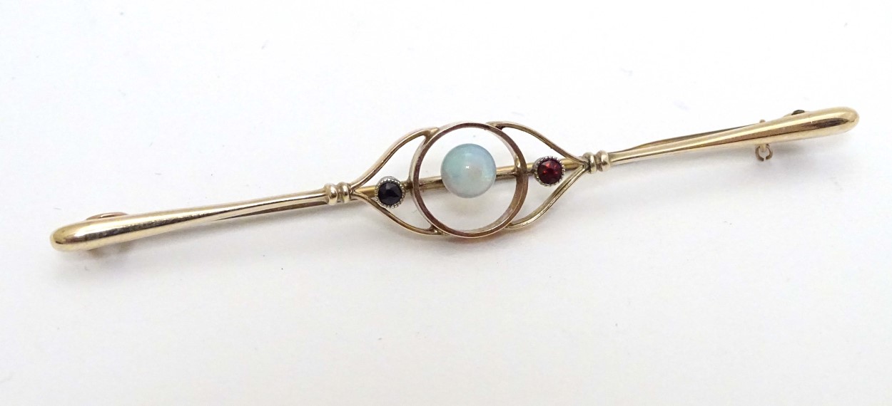 A 9ct gold brooch set with central opal flanked by garnets.