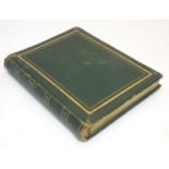 An empty photo album, green leather bound with gilt decoration to front back and spine,