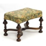 An early 20thC oak stool with floral upholstery and shaped seat,