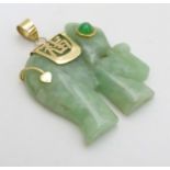 A carved jade pendant formed as a elephant with jade cabochon eye and 14kt gold mounts.
