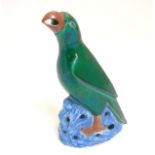 A Chinese export porcelain green parrot perched on a blue rock with iridescent glaze,