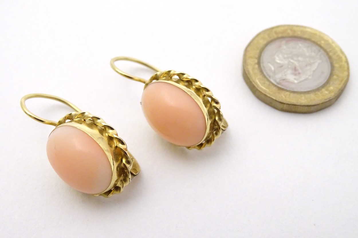 A pair of 18ct gold earrings set with coral cabochon .