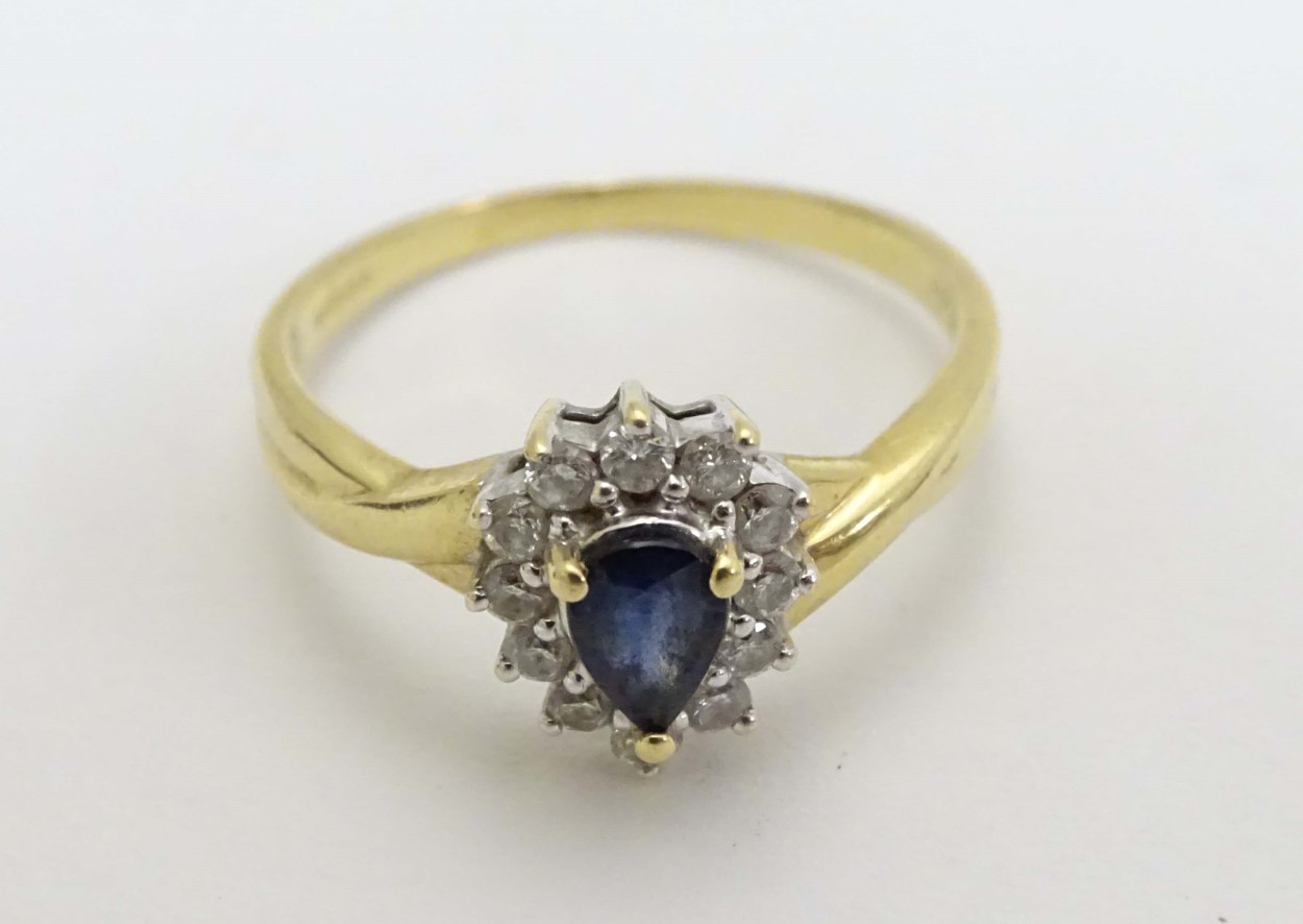 An 18ct gold ring set with central blue stone bordered by diamonds CONDITION: