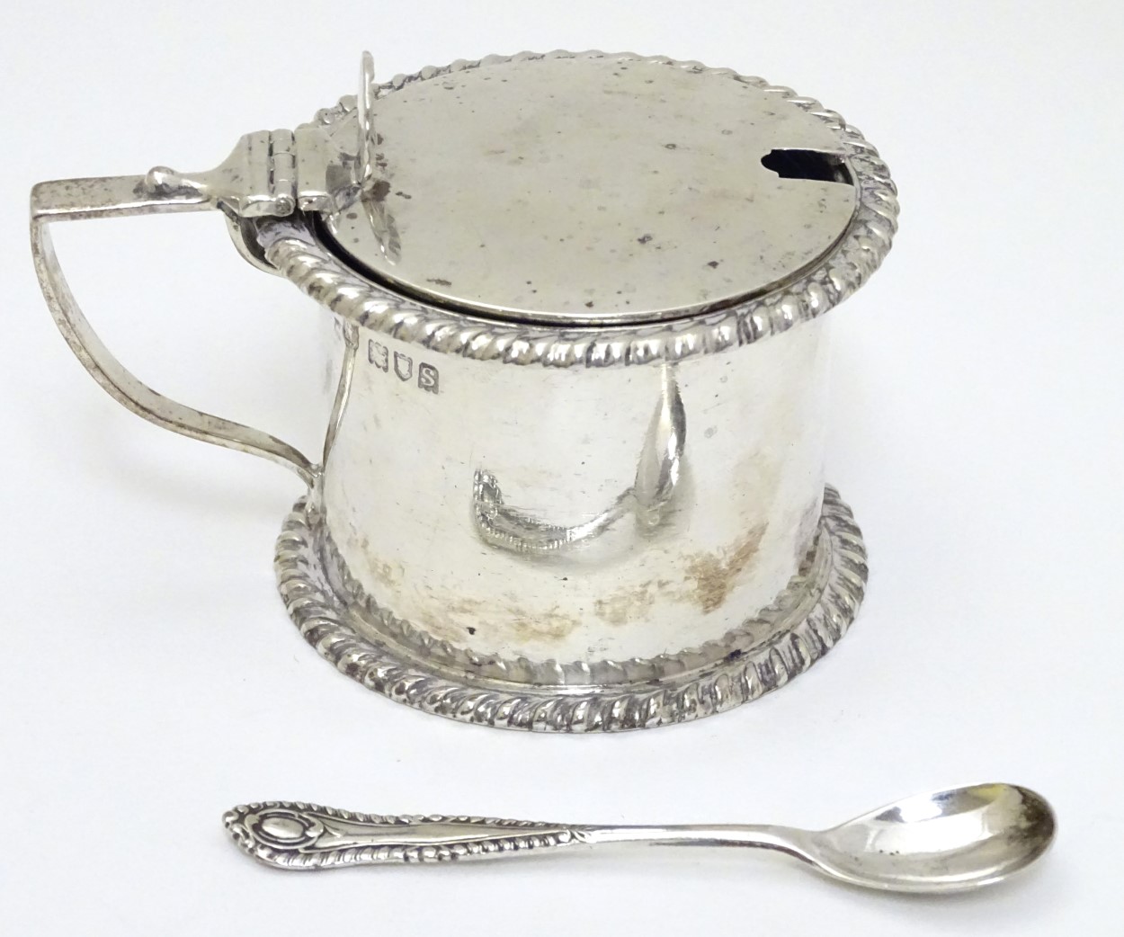 A silver mustard pot with hinged lid and blue glass liner,