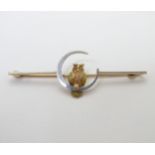 A 15ct gold and platinum bar brooch with owl and moon decoration 2" wide CONDITION: