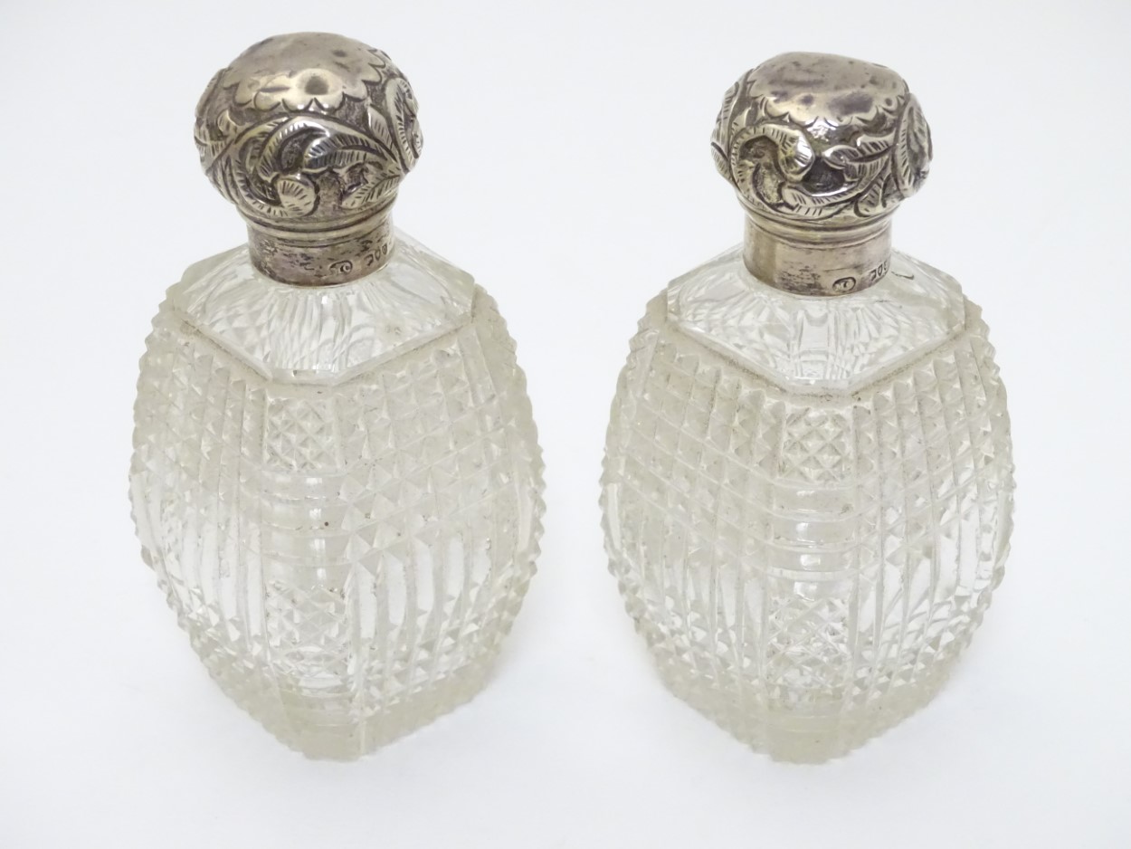 A pair of cut glass dressing table perfume / scent bottles with silver tops hallmarked London 1891