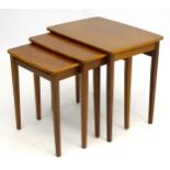 Vintage Retro : A nest of three teak graduated tables with trestle ends and bowed stretcher,